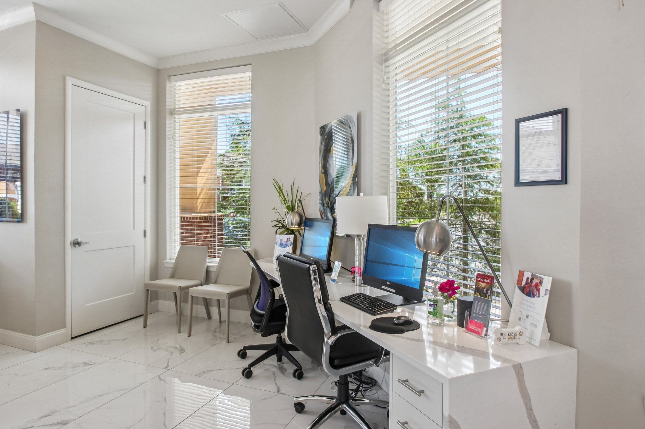 A white desk with a computer and a chair in front of a window with blinds.